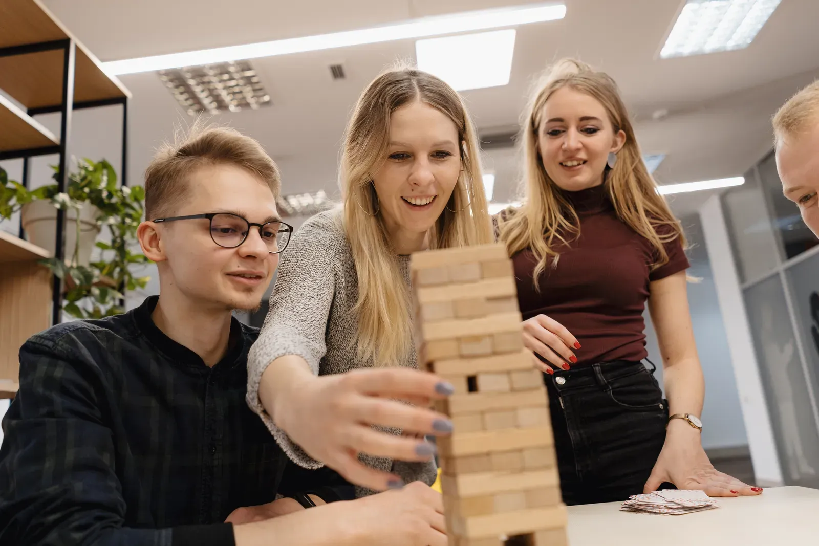 Tři mladí lidé společně hrají hru s věží z dřevěných kostek